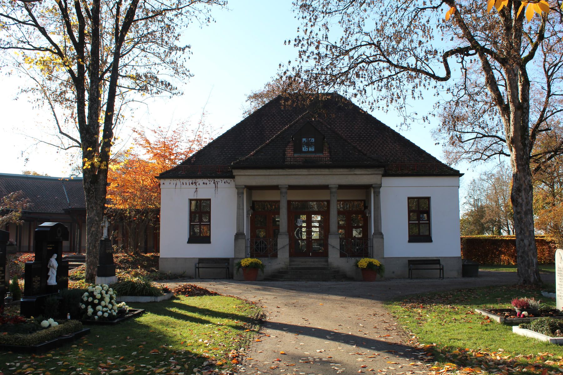 Historic cemetery building with a columned entrance among mature trees at Aubing Cemetery